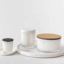 Load image into Gallery viewer, An image of 3 candles, 50cl with a wooden coloured lid, 30cl with a white lid and a 9cl with a black lid.  All of the candles are in white glass vessels with an MJM Home Fragrance logo
